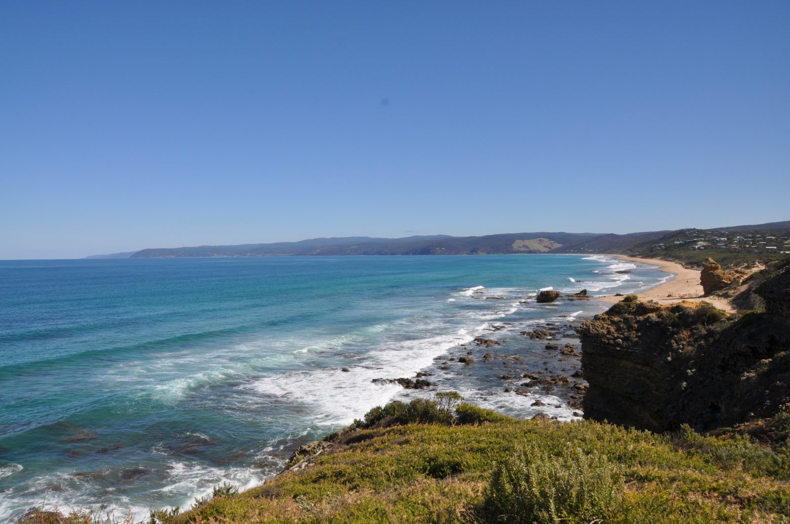 long sandy beach and wavy blue ocean off the great ocean road on a clear sunny day in victoria australia