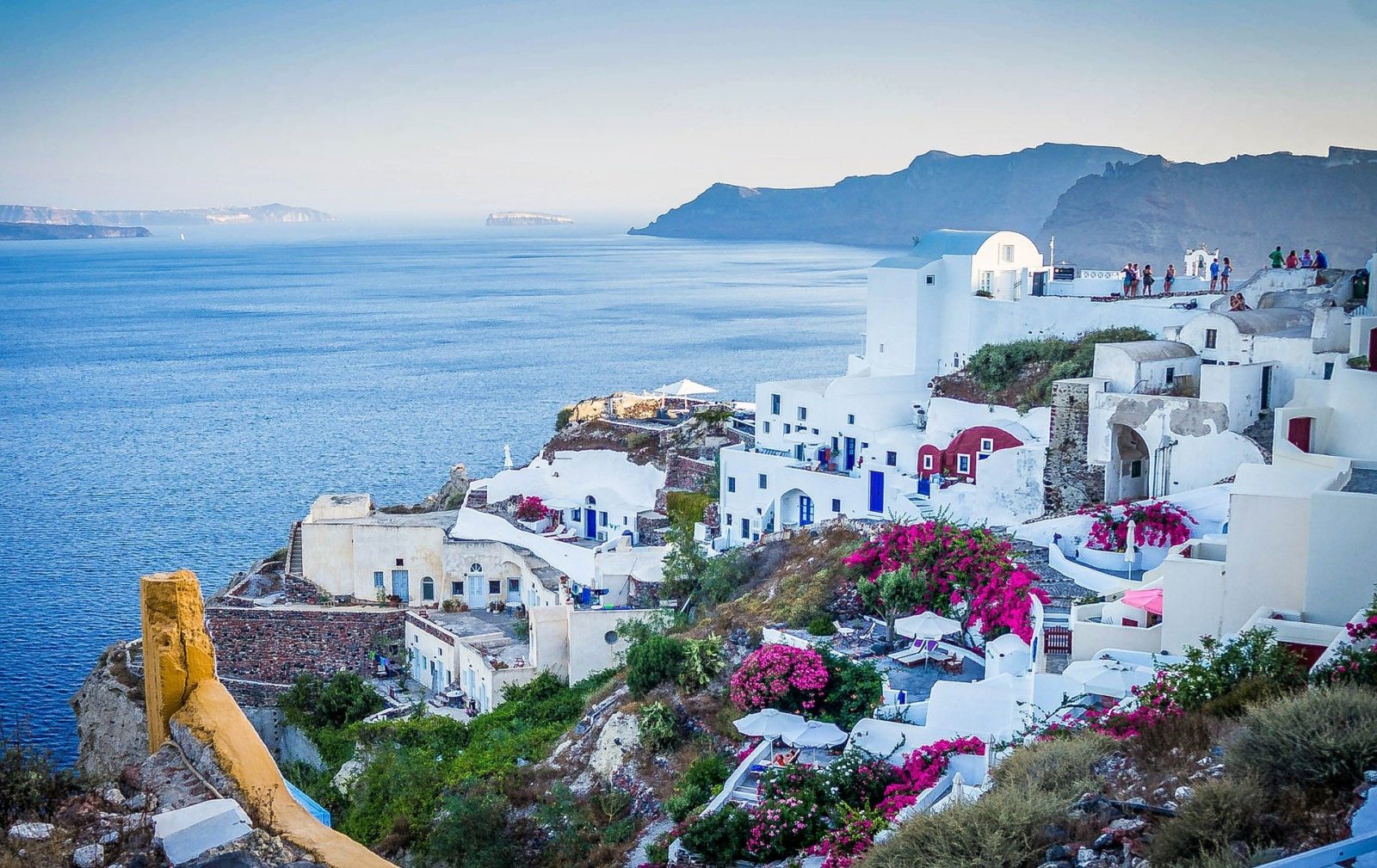 Santorini, Greece Beautiful city of Oia on a hill of white houses with blue  roof and windmills against dramatic pink sky, located in Greek Cyclades