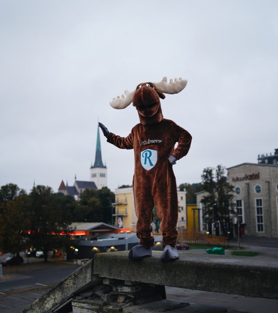 Rental Moose mascot posing with church tower in Tallinn, Estonia. Best things to do in Tallinn Estonia with Rentalmoose