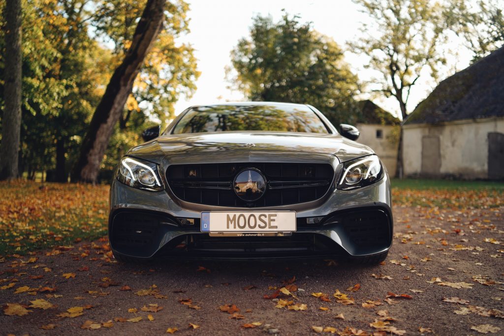 front view of mercedes benz sedan with custom Rental Moose license plate in a forest in estonia.