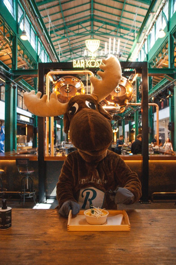 Rental Moose mascot posing with a bowl of thai soup in Hala Koszyki foodcourt in downtown Warsaw. Hala Koszyki is one of the best places to eat out in Warsaw Poland.