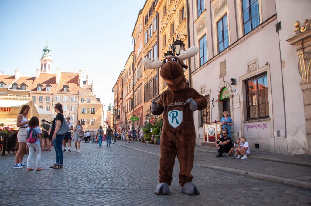 Rental Moose mascot posing in Warsaw Old Town Square. Sunny day in the heart of summer in the capital of Poland. 