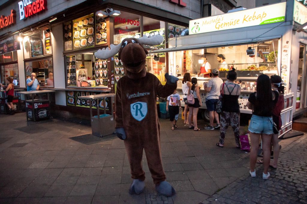 Rental Moose mascot standing next to busy Mustafa's Gemuse Kebap food stall. It is one of the best doner kebap in Berlin located in Kreuzberg, and one of the best places to eat in Berlin.