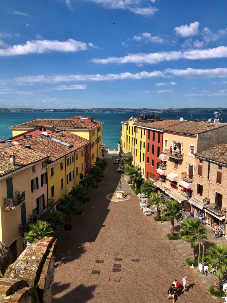 Yellow, traditional italian buildings and a small piazza in Sirmione right by the crystal-clear Lago di Garda. See the best parts of northern italy with our italy road trip itinerary.