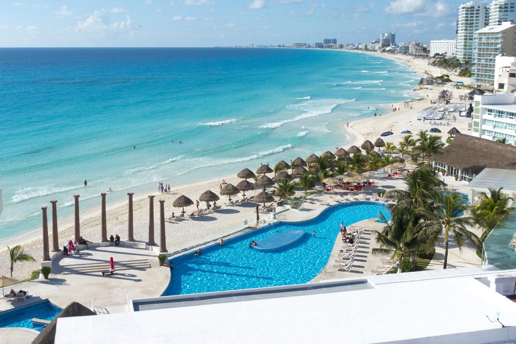 Beautiful seaside resort in Cancun, Mexico. Pristine sandy beach, turquoise water and an empty pool. Enjoying the beach is one of the best things to do in Cancun.