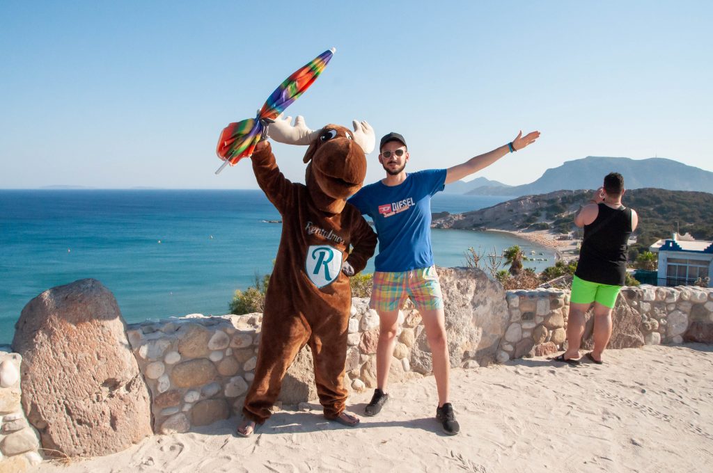 Rental Moose Mascot posing with tourist on the coast of a sandy beach in Northern Cyprus. Find the best beach in Cyprus with our curated cyprus road trip itinerary.