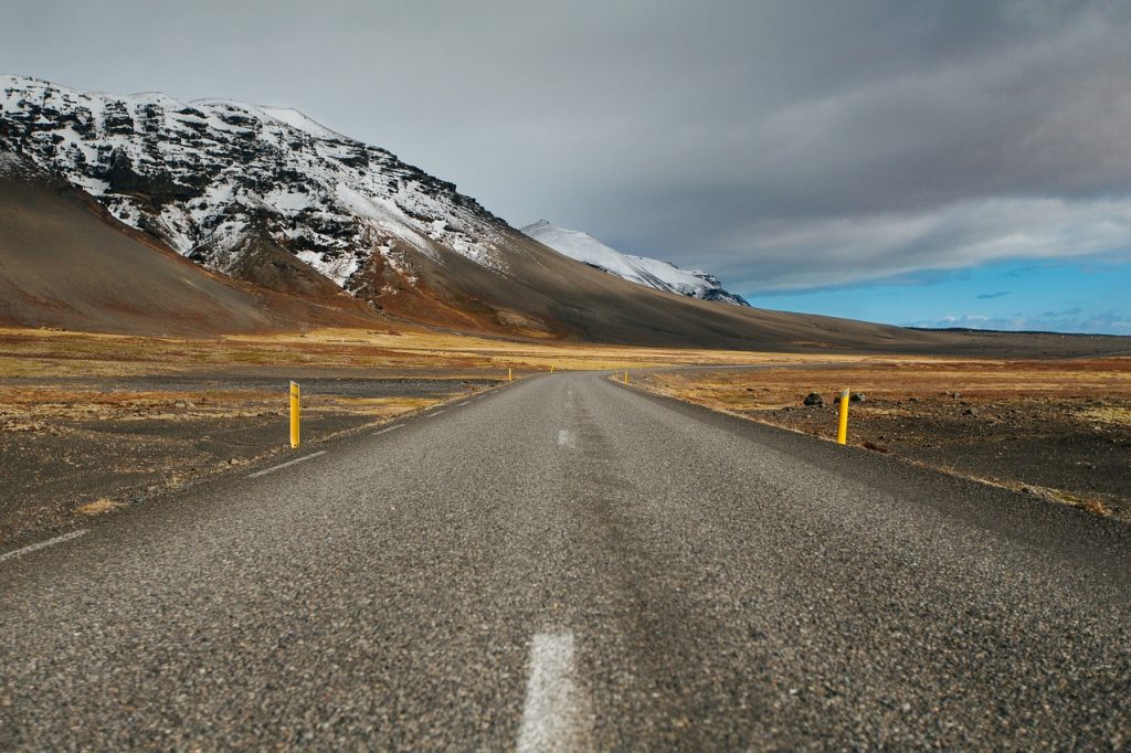 A road in iceland through the endless plains, snowy mountains in the distance. The Ring Road loops around the beautiful country of Iceland.