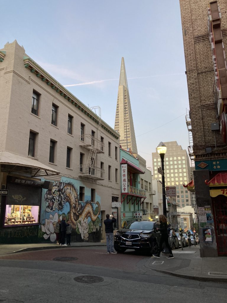 Colorful dragon mural in San Francisco's Chinatown seen at sunset. Transamerica Pyramid visible in the background.